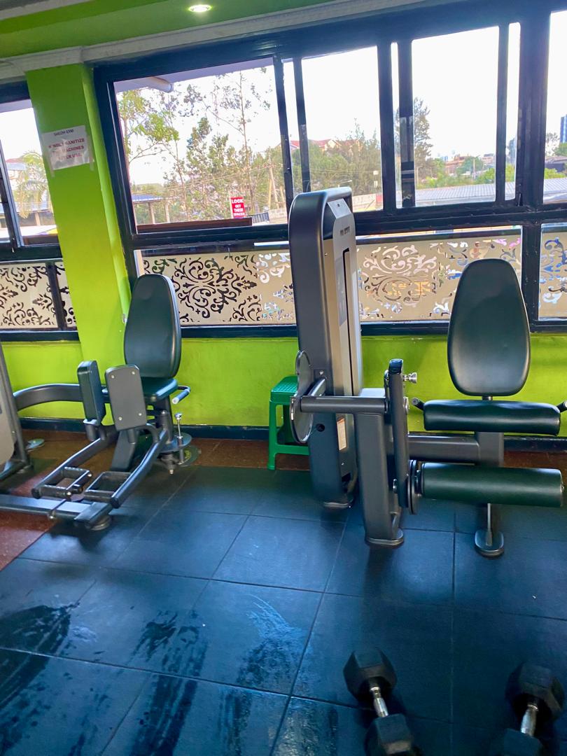 Leg extension and hip abductor machines with dumbbells on the floor at Shiloh Gym